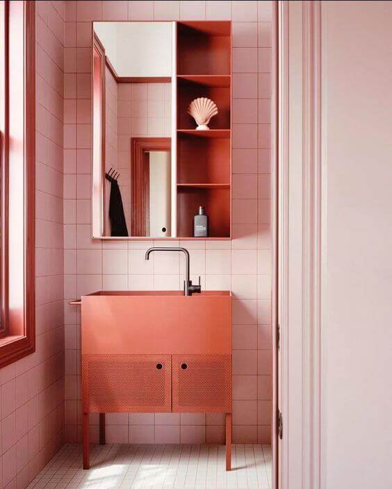 Banheiro retro decorado com gabinete na cor pêssego e revestimento rosa claro