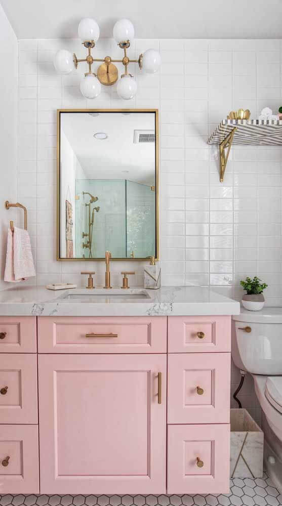 Banheiro retro com gabinete rosa claro e detalhes em dourado