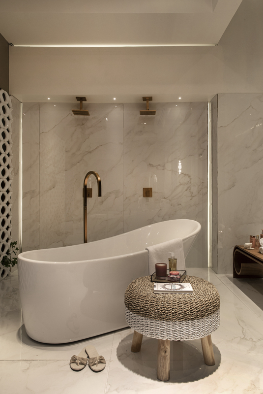 Banheiro com chuveiro dourado duplo e banheira branca
