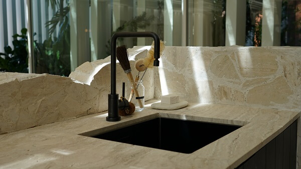 Banheiro com torneira preta na bancada de granito