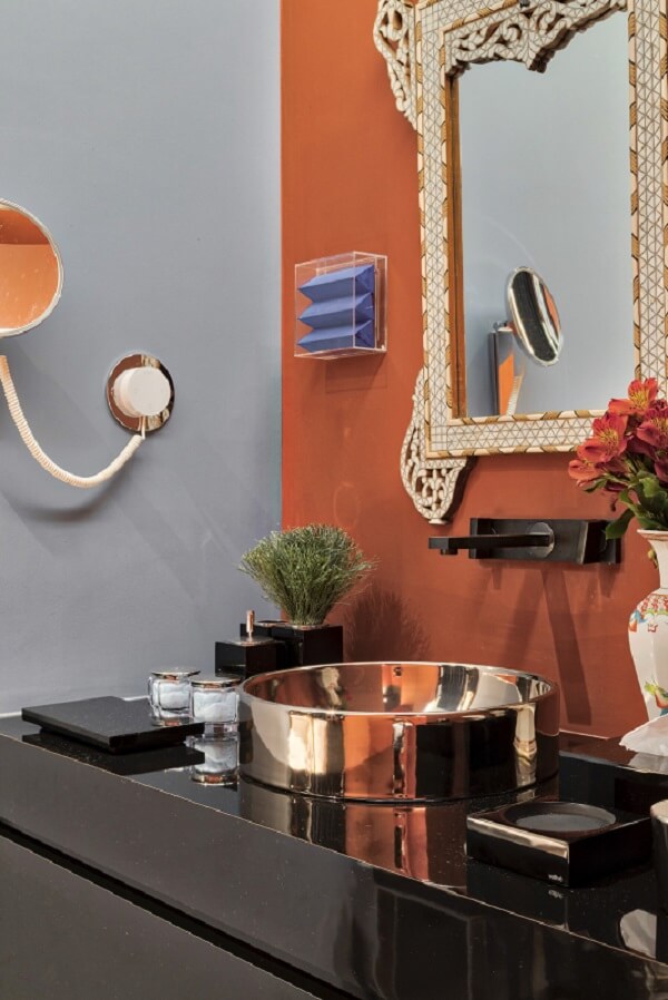 Banheiro moderno com torneira de parede preta e cuba redonda dourada