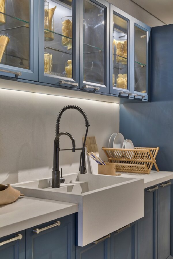 Cozinha azul com bancada branca e torneira preta em destaque