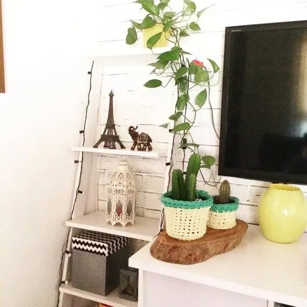 Na sala de estar você pode colocar a escada decorativa ao lado do rack. Fonte: Rosane Brandão