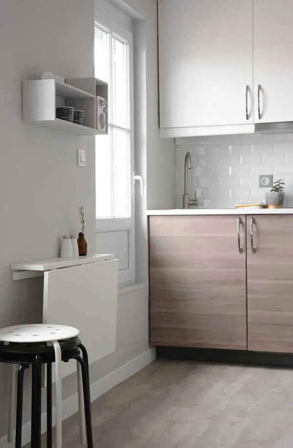 Cozinha compacta com decoração clean e mesa dobrável de parede.