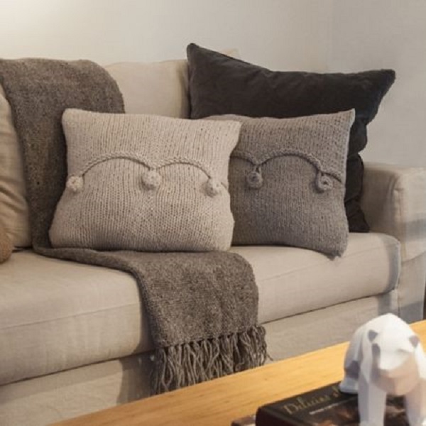 Sofá cinza com almofada de tricô e manta