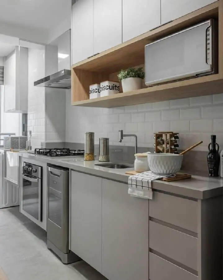 cozinha compacta decorada com armário de cozinha cinza e branco e nicho de madeira Foto Jeito de Casa