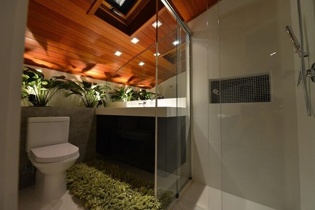 Banheiro feminino aconchegante com plantas e tapete verde