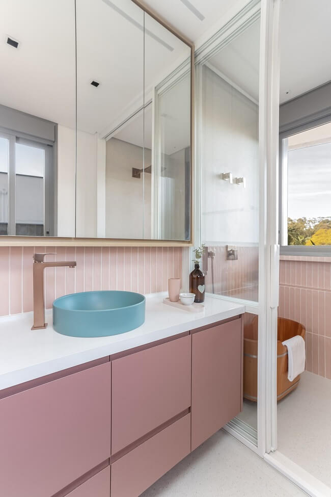 Banheiro feminino com gabinete rosa e cuba redonda