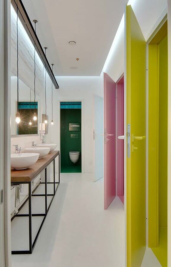 banheiro feminino decorado com bancada de madeira e porta amarela e rosa Foto Archdaily