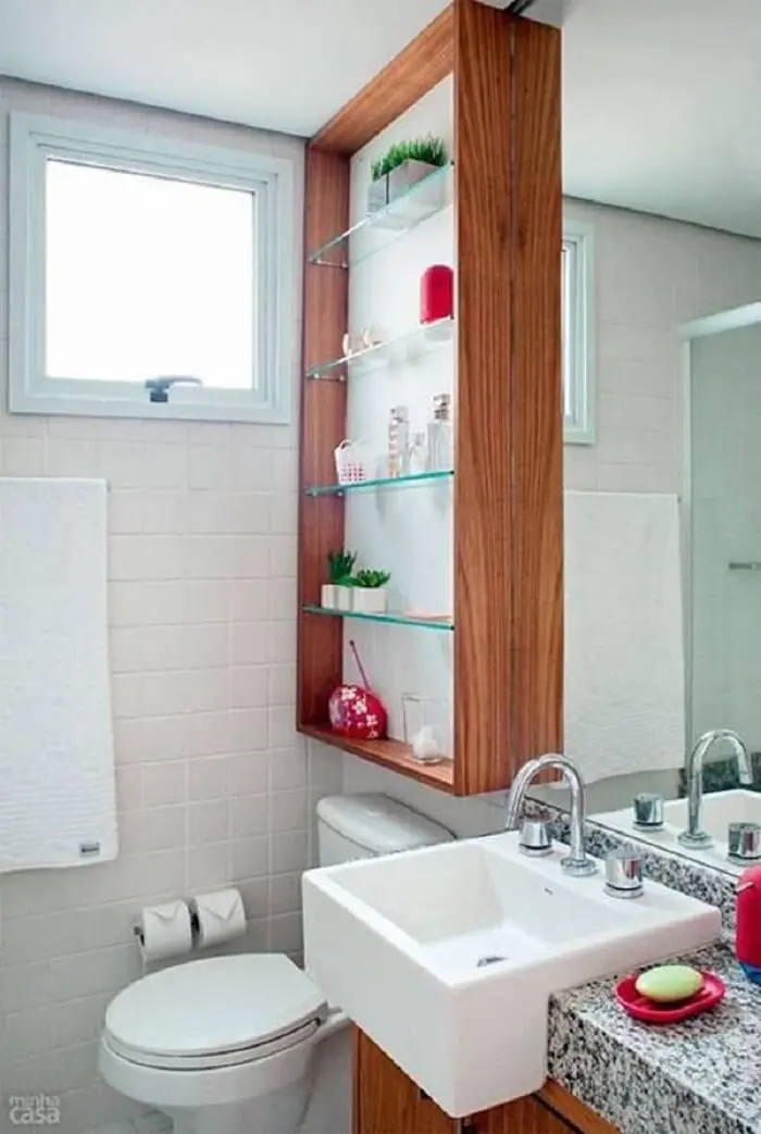 Prateleira para banheiro de vidro embutida na parede posicionada acima do vaso sanitário