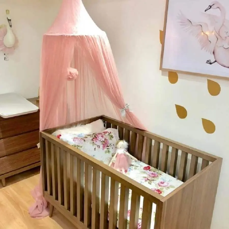 quarto de bebê simples decorado com móveis de madeira e dossel rosa Foto Baby Road