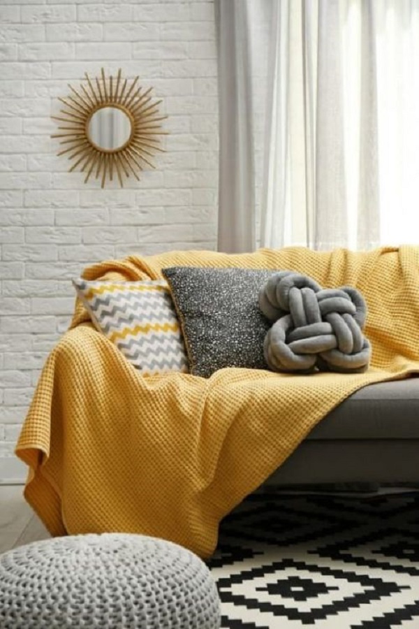 Sala moderna com sofá cinza e manta amarela
