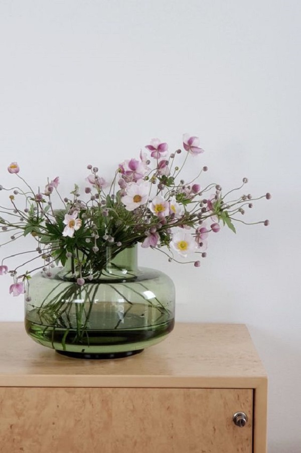 Vaso de vidro verde com flores cor de rosa