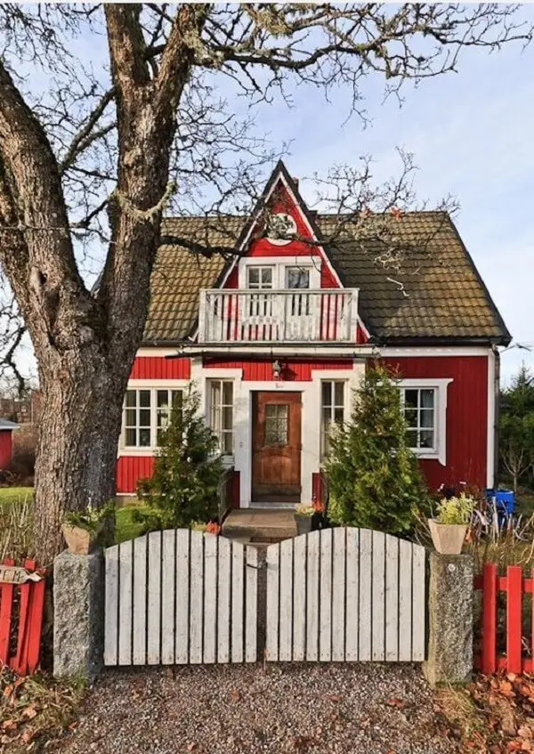 Casa vermelha com portão de madeira branco