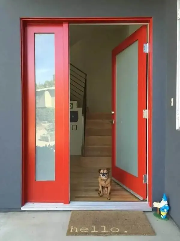 O capacho completa a decoração da porta de entrada da casa com porta vermelha
