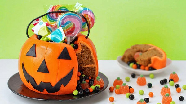Bolo de Halloween em formato de abóbora serve de suporte para doces